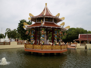 Amidst the trees and buildings, a Chinese arch sits at the center of a water fountain.