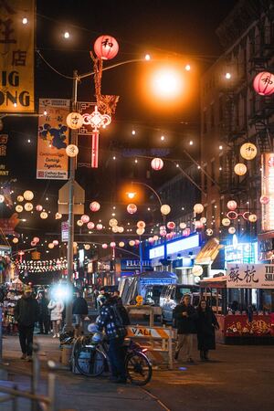 In Manhattan Chinatown, individuals on bicycles actively traverse the streets while pausing and gazing at the bustling Chinese shops.