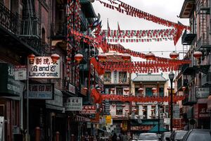 A group walks under red lanterns in San Francisco's Chinatown, surrounded by Chinese buildings. Concept, Largest Chinatown in the United States.