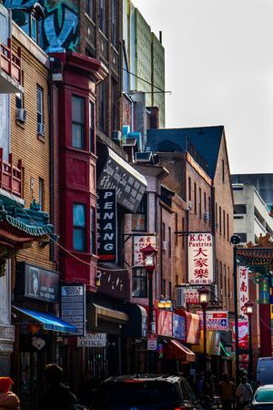 People walk among parked cars and the Chinese buildings in Chinatown, Philadelphia. Concept, Largest Chinatown in the United States.