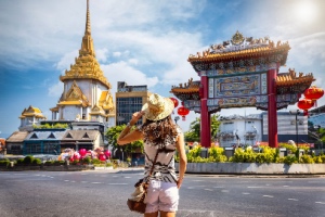 A female tourist stands before the Chinatown Gate on Yaowarat Road, Bangkok, showcasing Chinatown architecture.